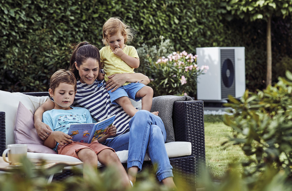 mama czyta dzieciom w ogrodzie, w tle widać pompę ciepła