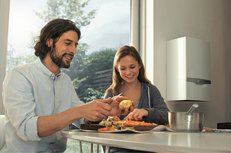 para przygotowuje obiad w kuchni, a w tle widać niewielką pompę ciepła